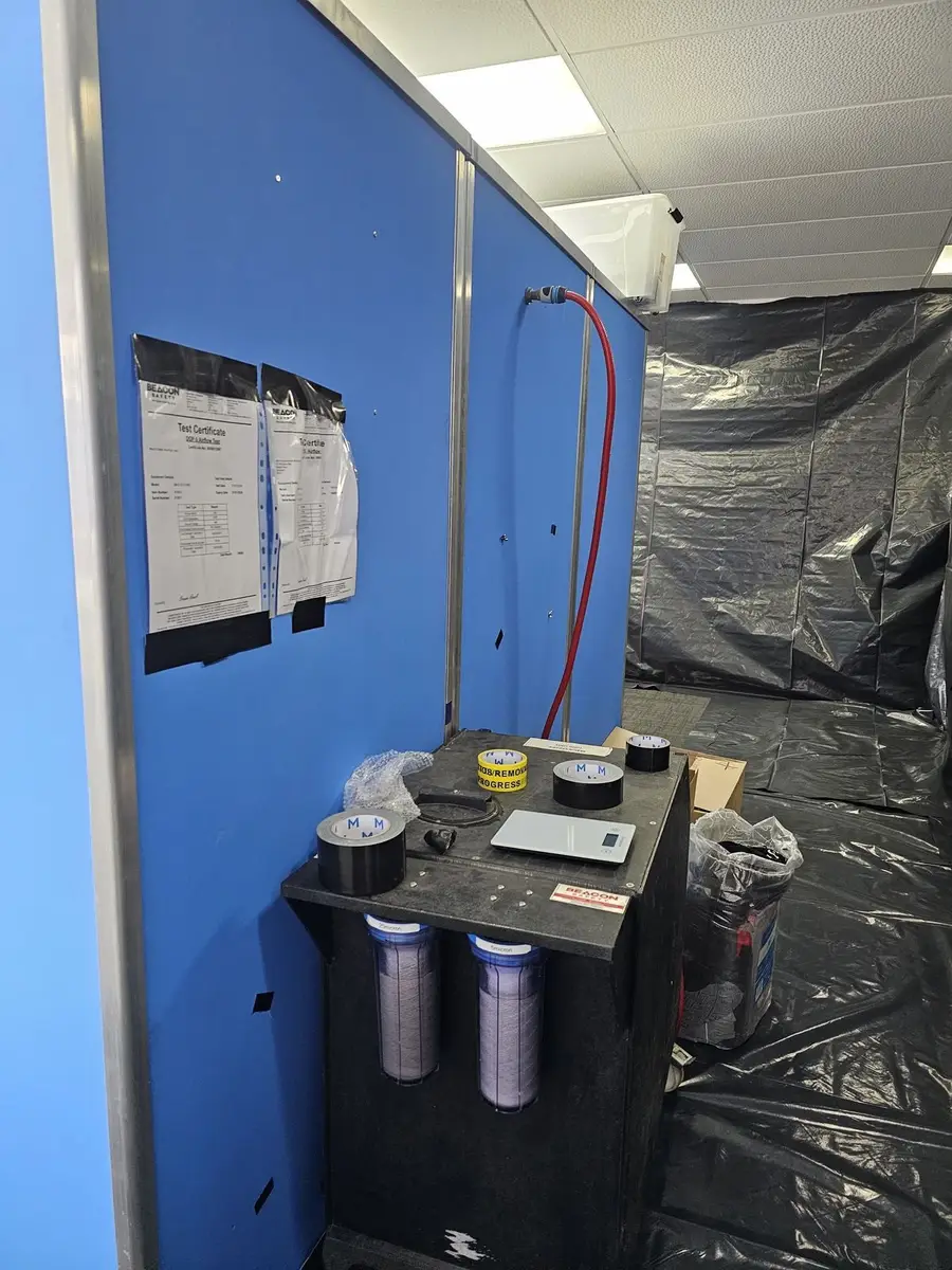 Air monitoring pumps set up beside the enclosure during asbestos removal in an office