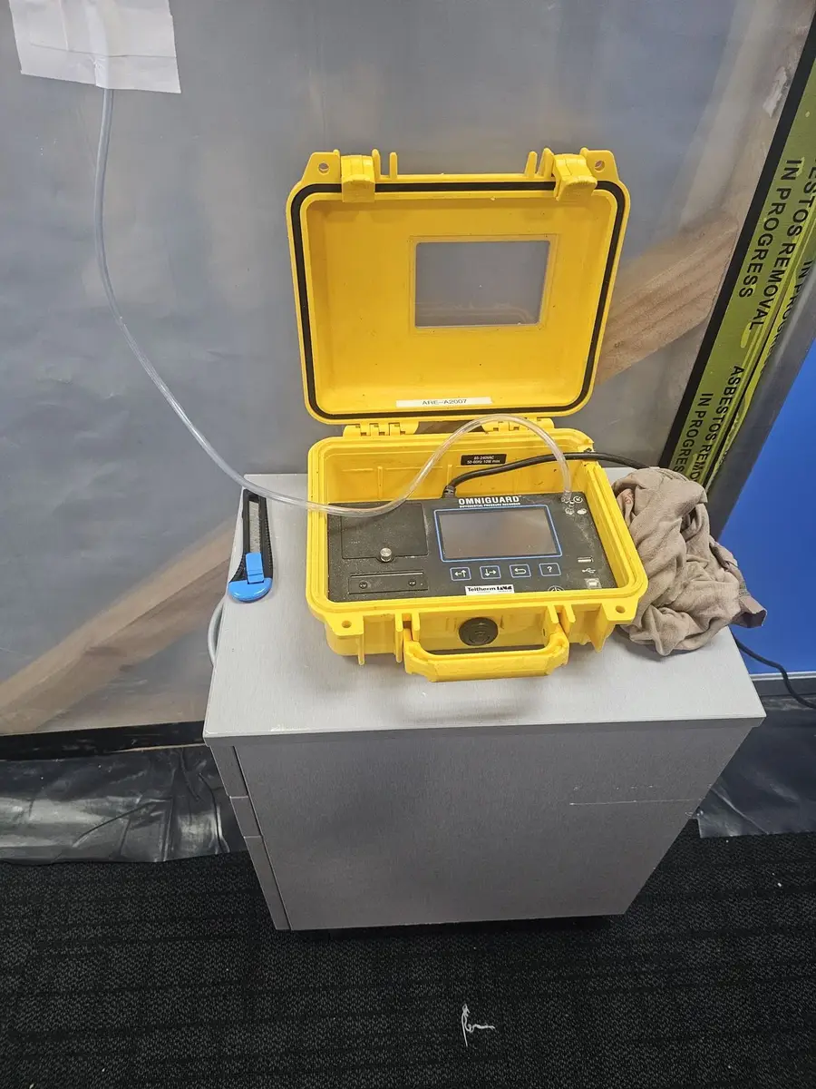 Air sampling pump in its yellow case during asbestos removal