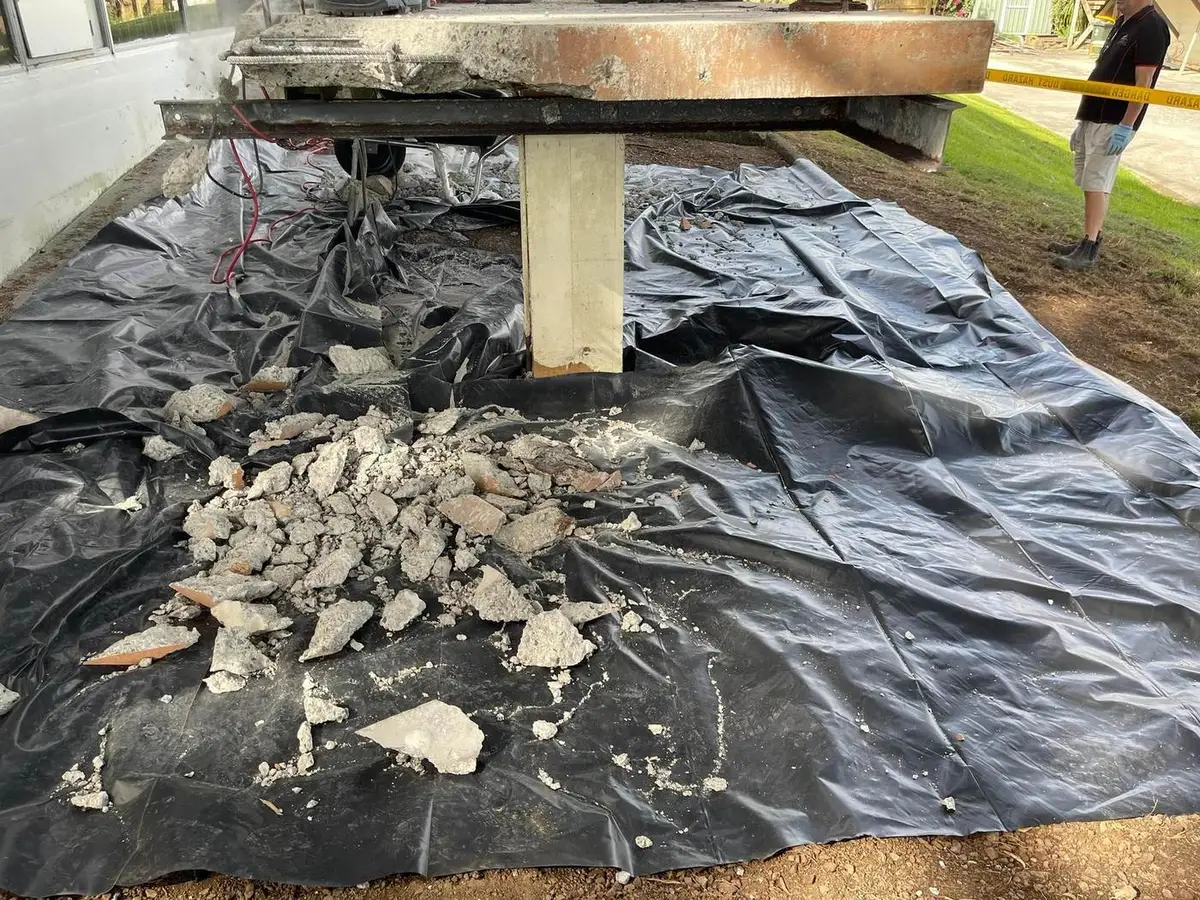 Asbestos-cement fragments collected on poly sheeting for disposal
