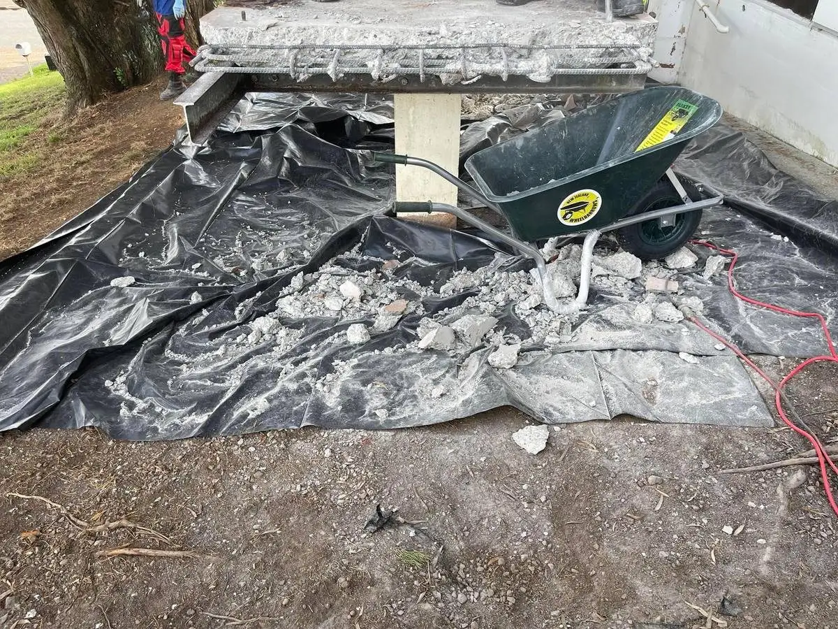 Asbestos debris on the black poly ground sheet at the removal site