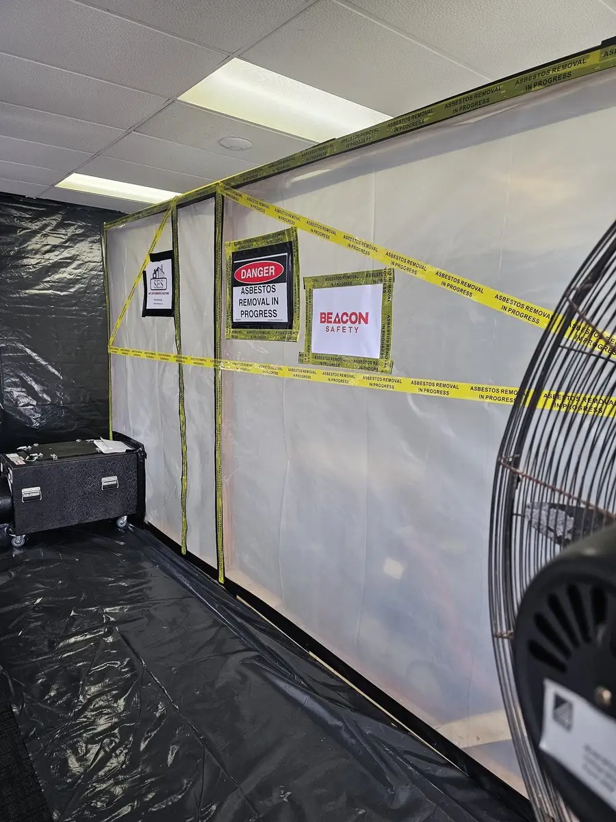 Asbestos enclosure with negative air unit running in an office