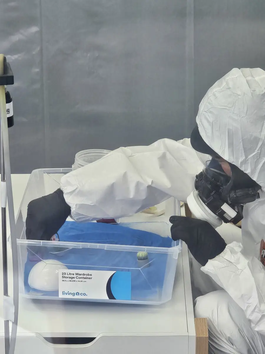 Operative in PPE and respirator bagging samples inside the enclosure