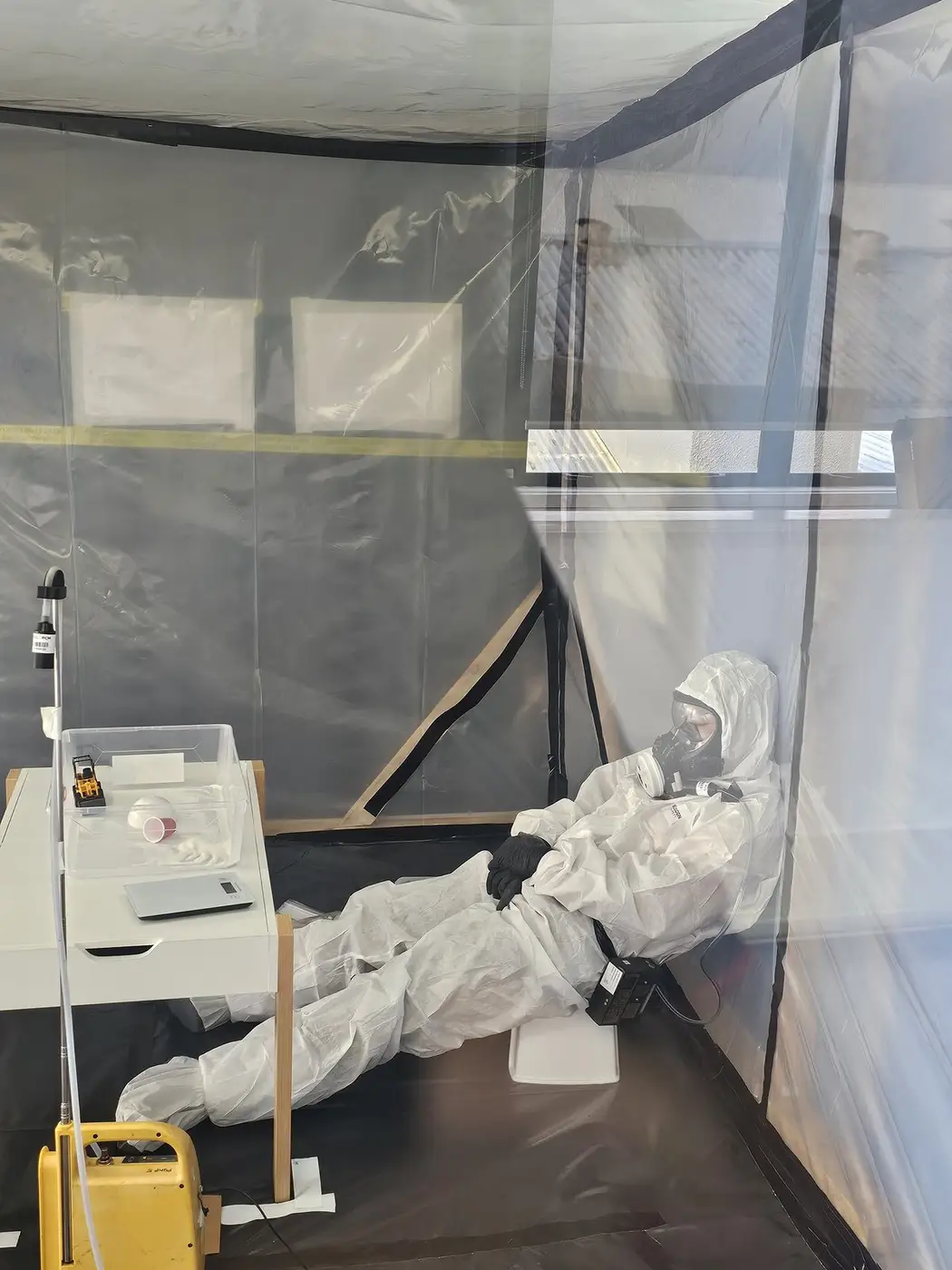 SES operative crouched working on the enclosure floor in full PPE