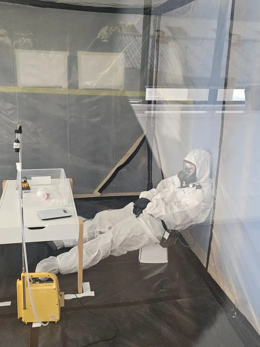 SES operative in full PPE removing material at floor level inside the enclosure