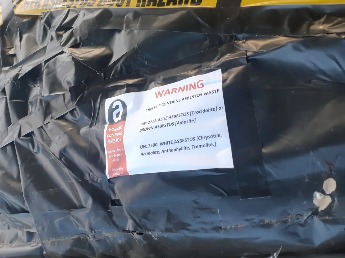 Asbestos warning label on a wrapped waste bag