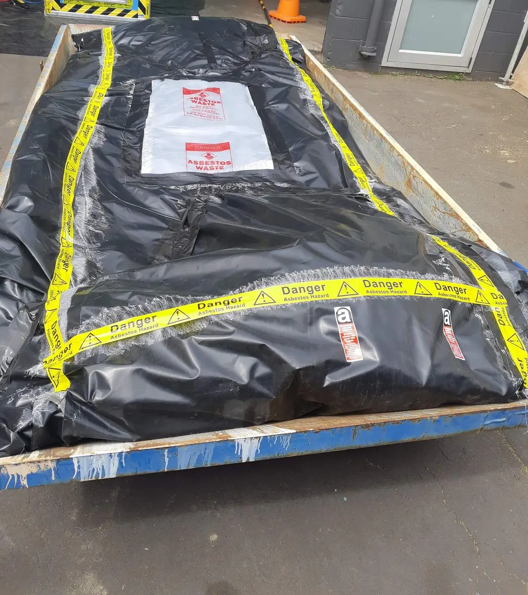 Asbestos waste wrapped in black poly on a trailer for licensed disposal