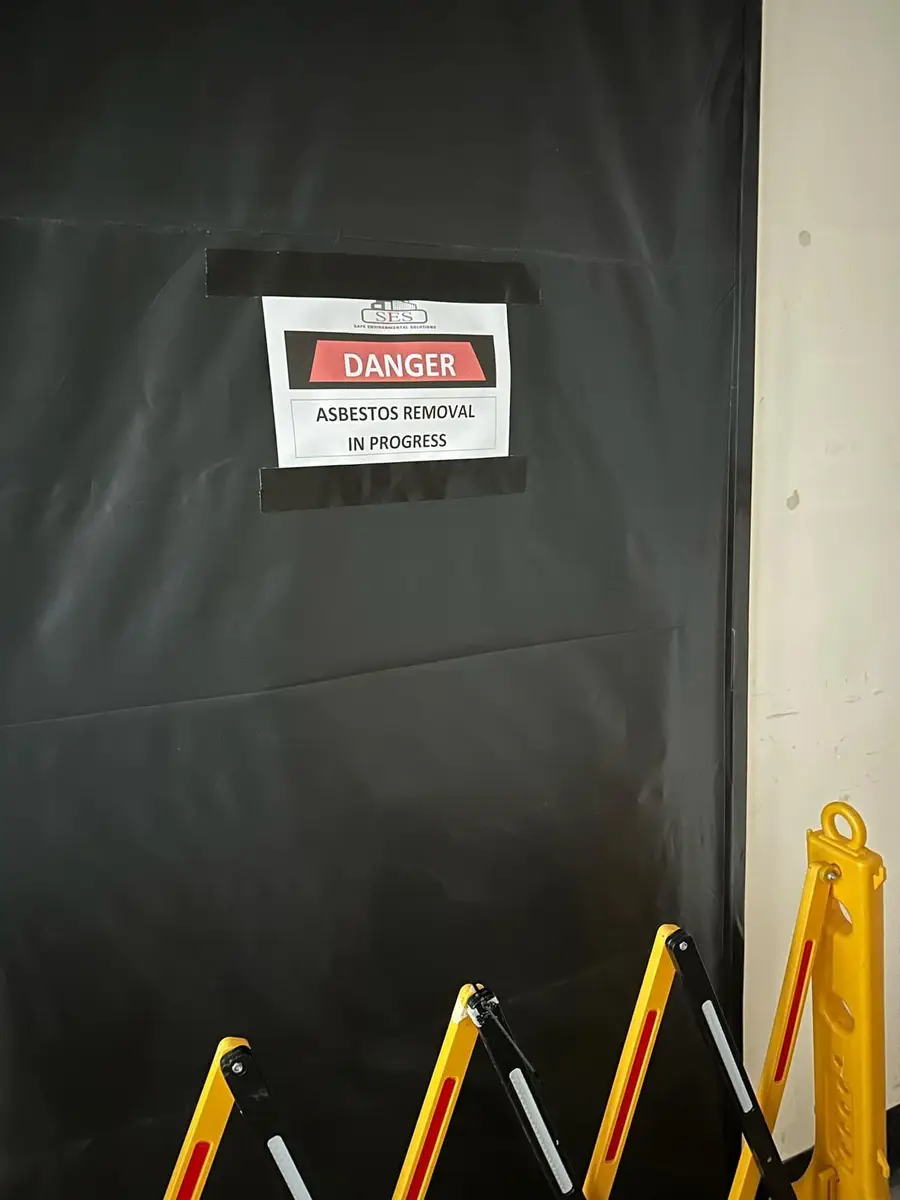 Black poly door with danger asbestos removal in progress sign
