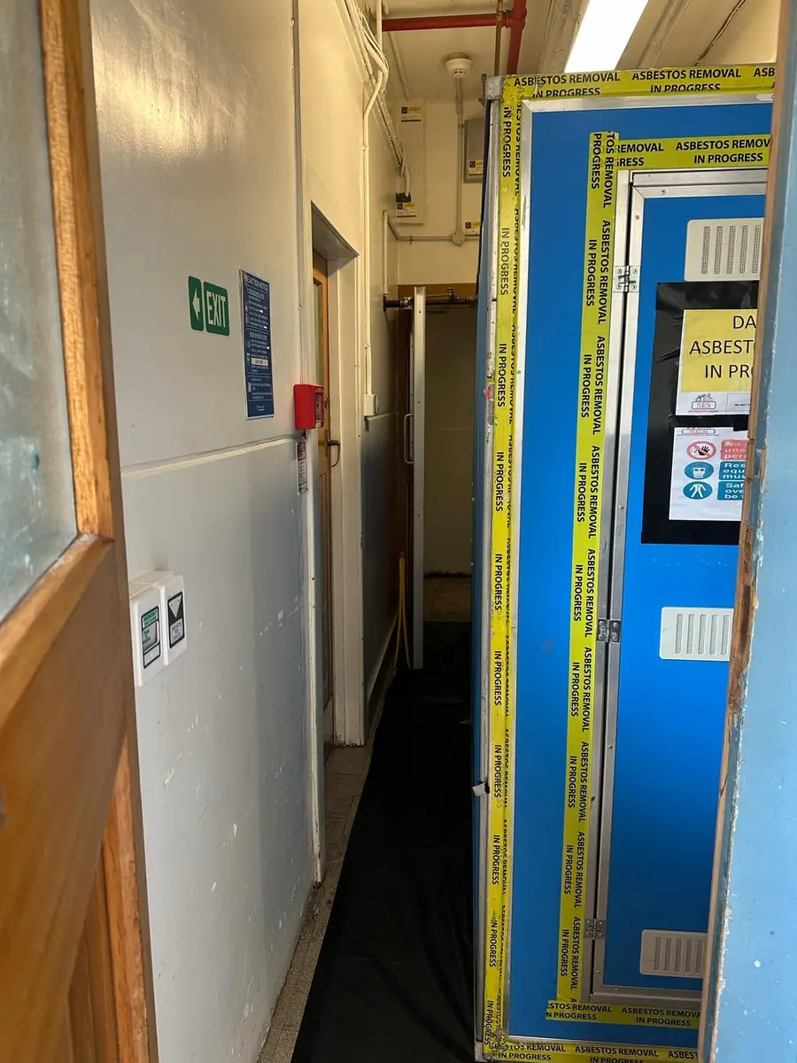Corridor enclosure door with blue decontamination unit and signage