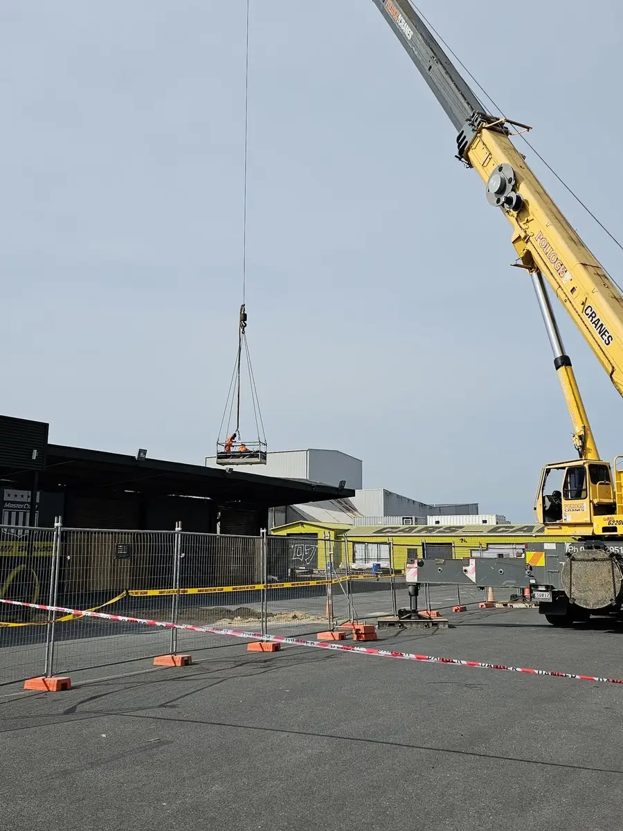 Crane lifting the work platform to the commercial asbestos roof