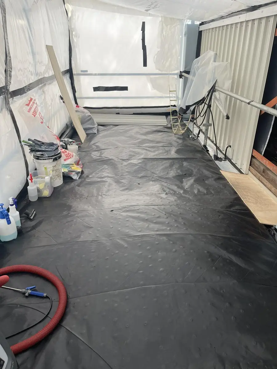 Decontamination unit with black poly floor sheeting during asbestos removal