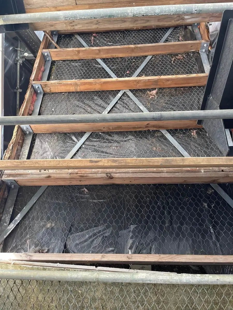Dismantled steel frame and timber laid on poly sheeting during the removal