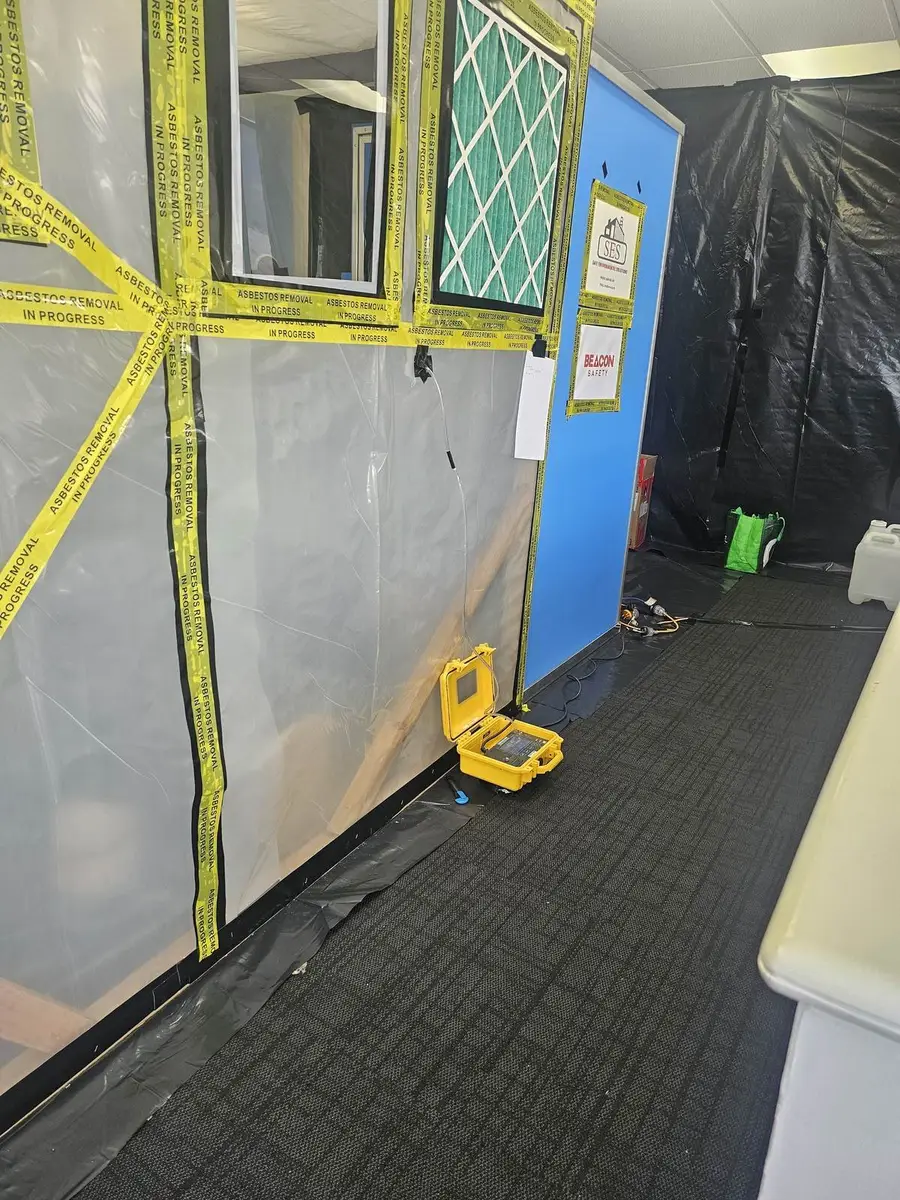 Enclosure wall with HEPA filter and pressure gauge during office asbestos removal