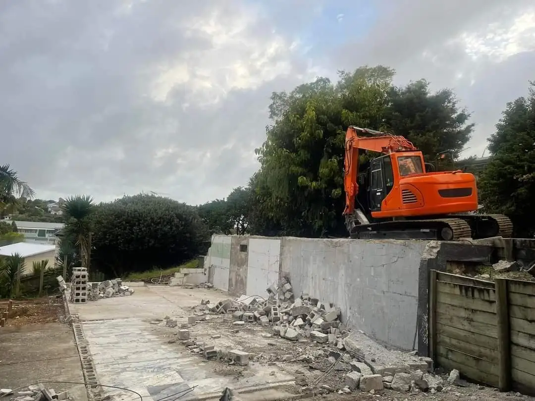 Excavator taking down the block wall at the sub-division