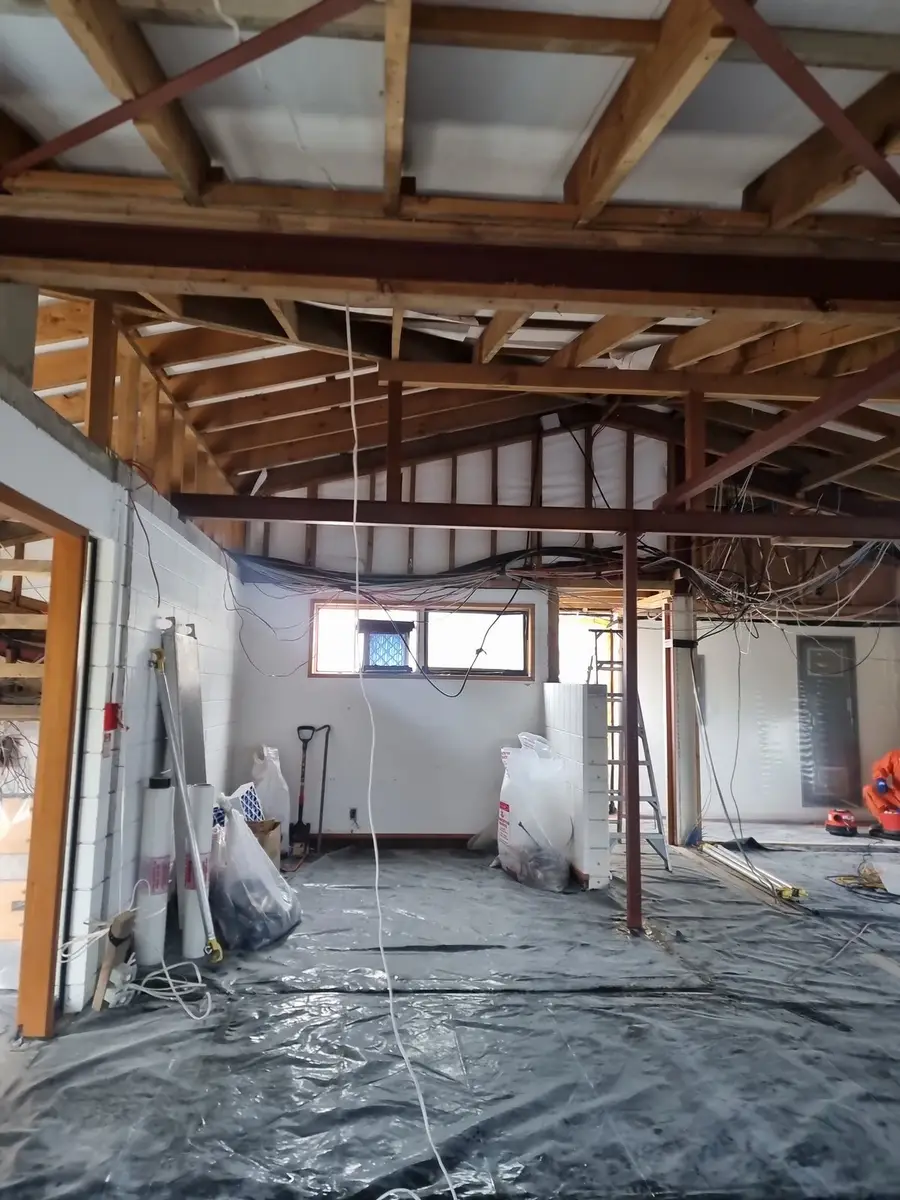Office strip-out with roof trusses exposed and black poly floor