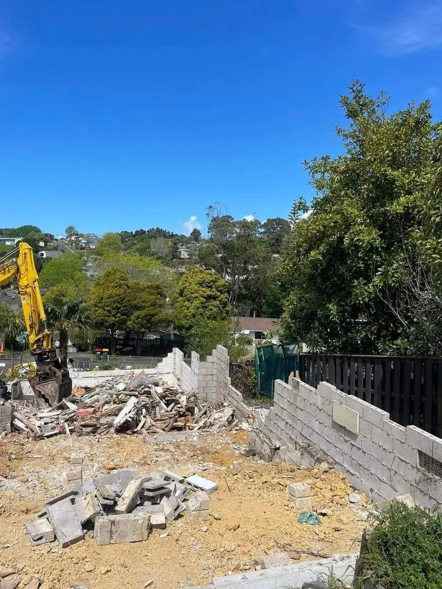 Excavator demolishing a block wall