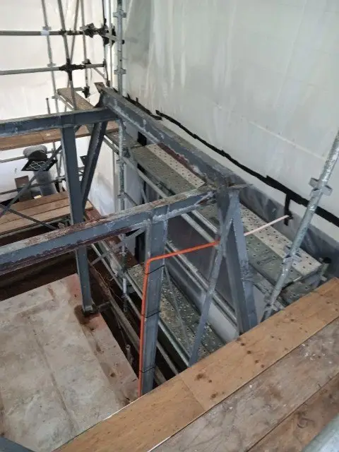 Scaffold enclosure around the steel beams during asbestos-cement removal