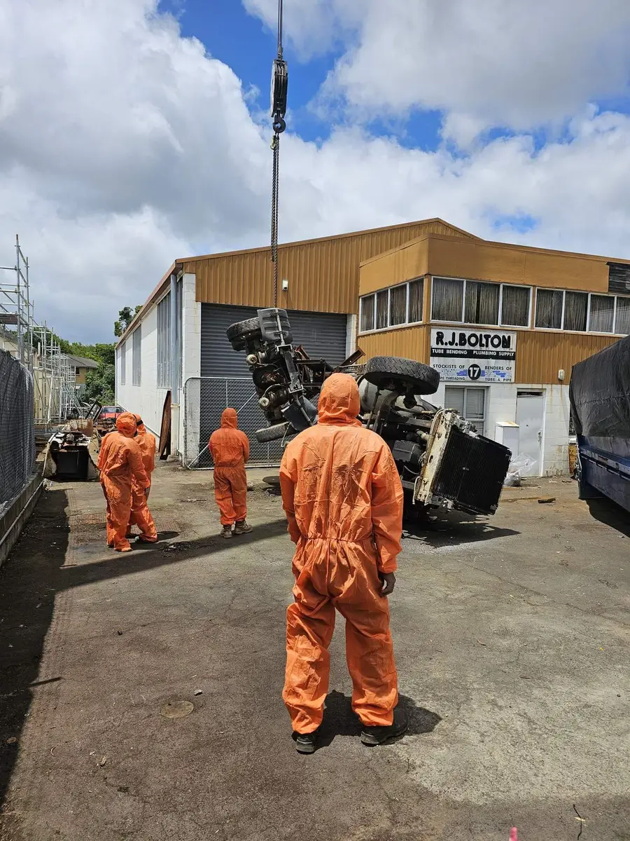 SES crew in orange PPE directing the crane lift of contaminated plant