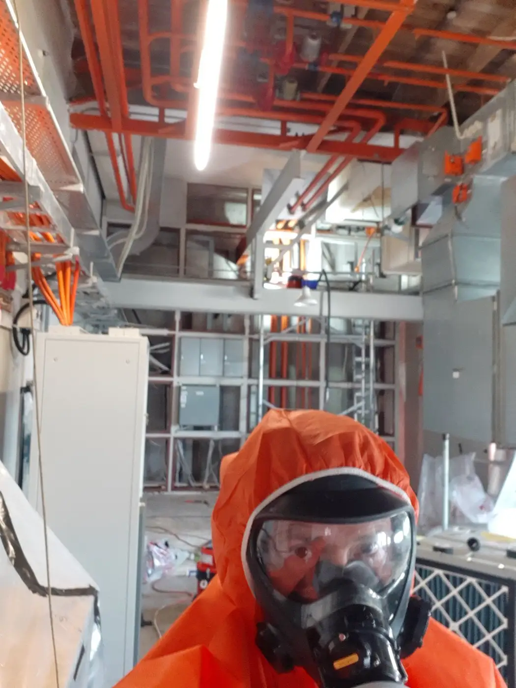 SES operative in orange PPE and full-face respirator in a commercial building