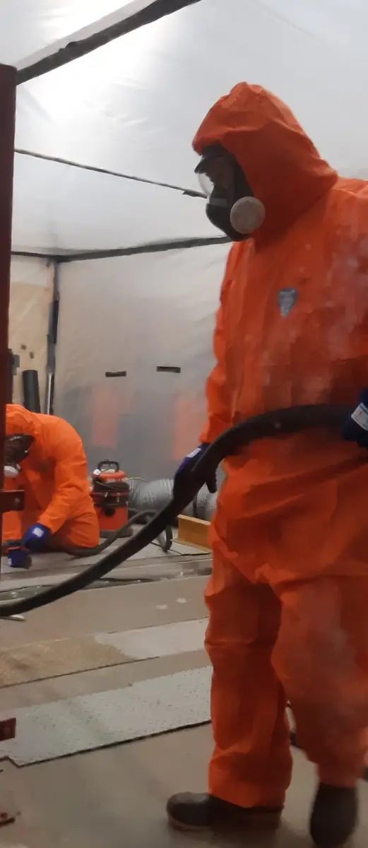 SES operative in orange PPE with vacuum hose inside the enclosure