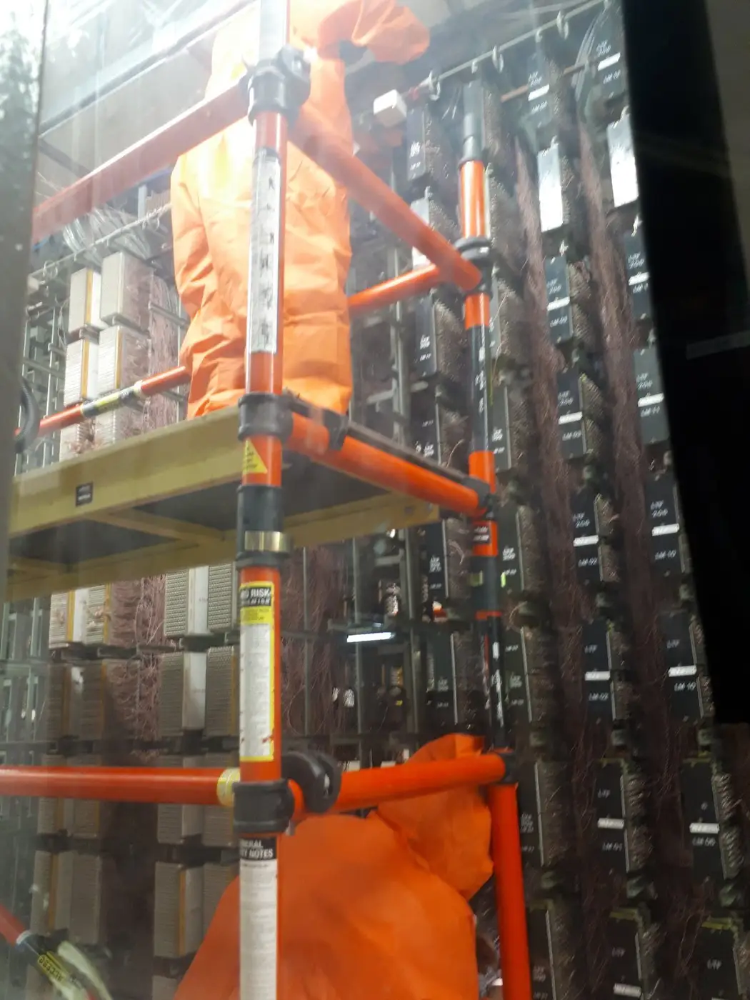 SES operative on scaffold between equipment racks during telecom exchange asbestos removal